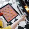 crop woman putting cookies in oven in kitchen